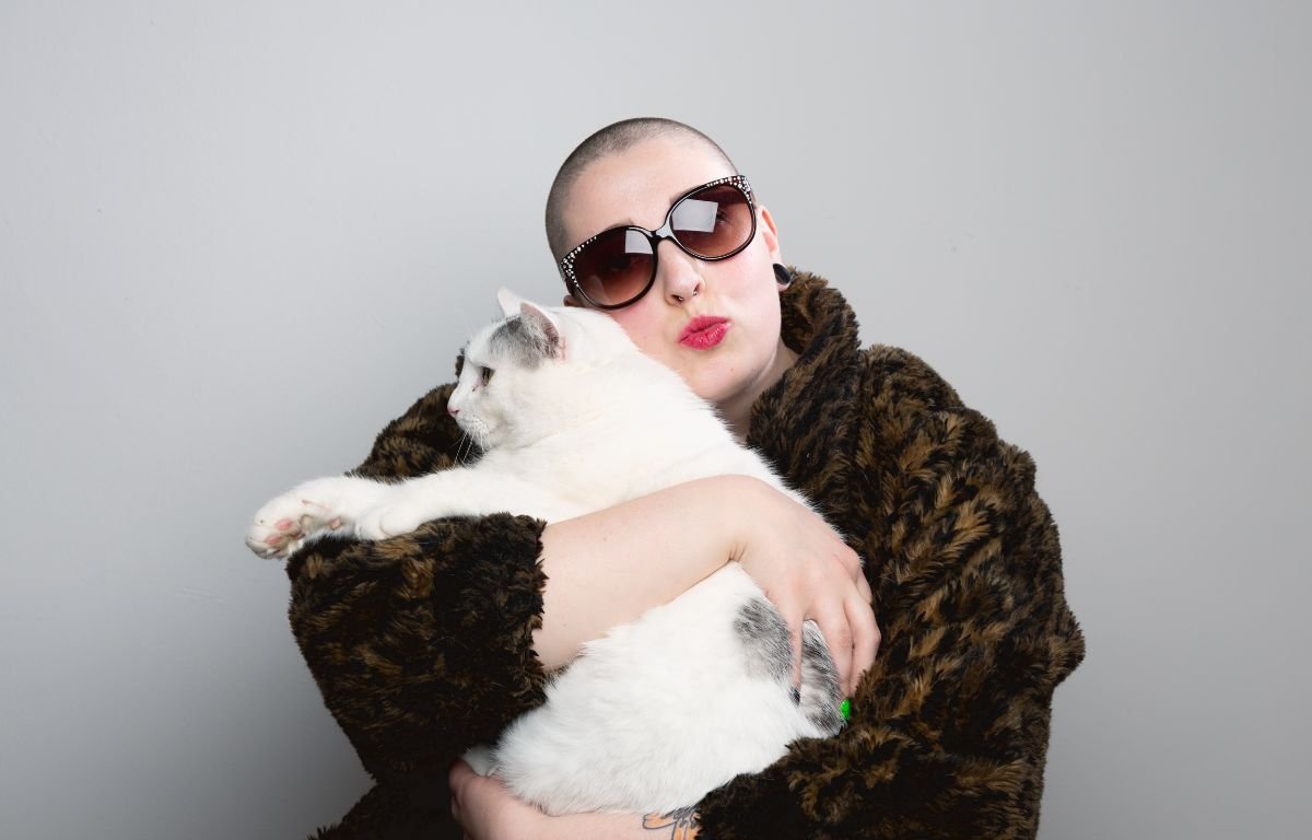 Znakovi da ste Vi zapravo mačka – žena u naočarima grli belu mačku i mačka mirno leži u naručju