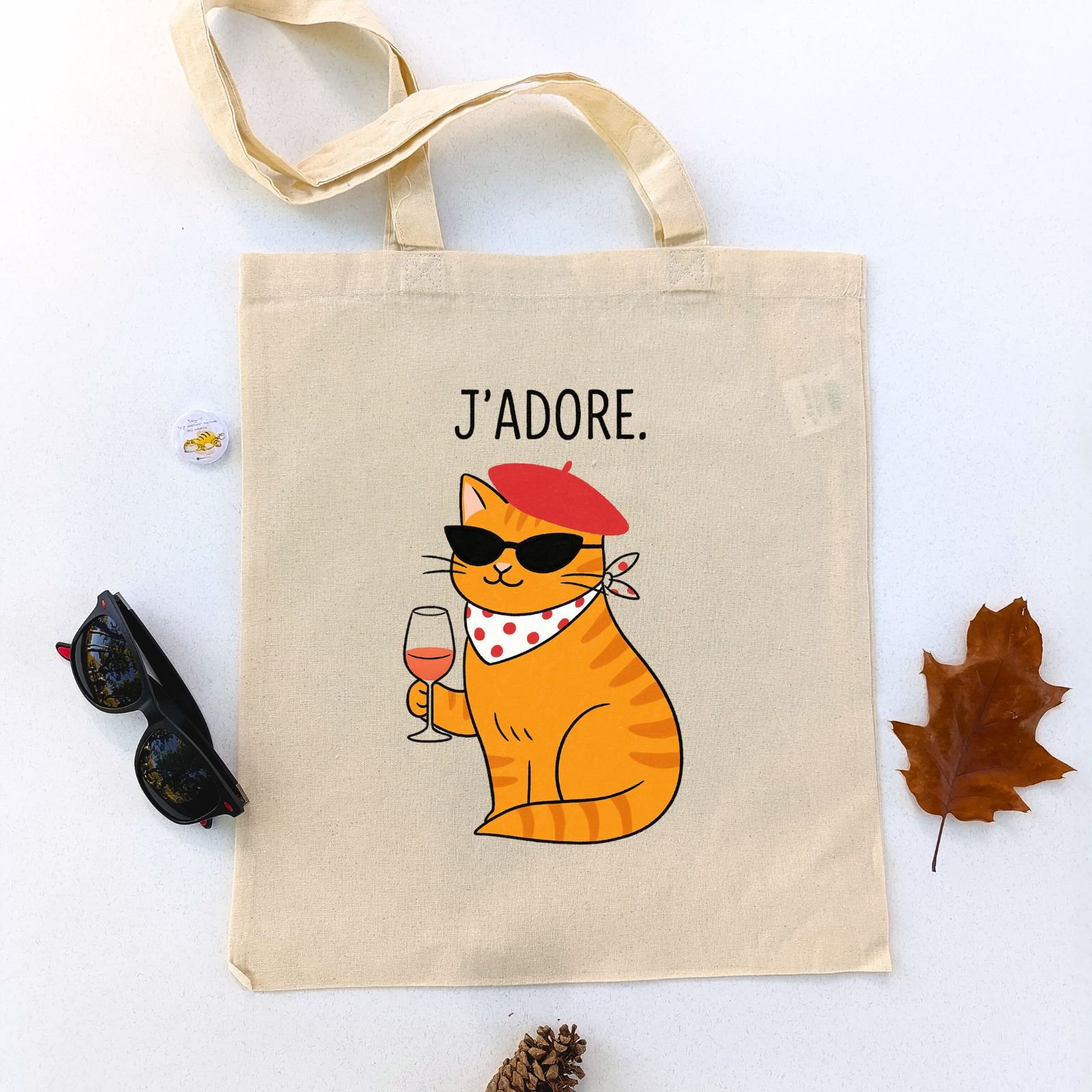 Ceger Mjau u Parizu sa ilustracijom narandžaste mačke sa beretkom, naočarima za sunce i čašom vina u šapi, uz natpis „J’adore“. Poklon za ljubitelje mačaka i francuskog šarma.