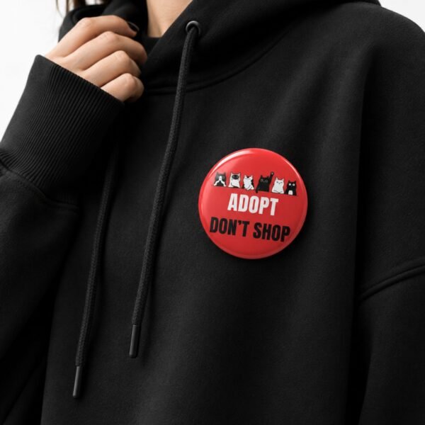 Crveni Adopt Don’t Shop bedž zakačen na crnom duksu