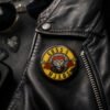 Guns N Mjaus rock bedž sa mačkom zakačen na crnoj kožnoj jakni – originalan dodatak za ljubitelje mačaka i rock muzike