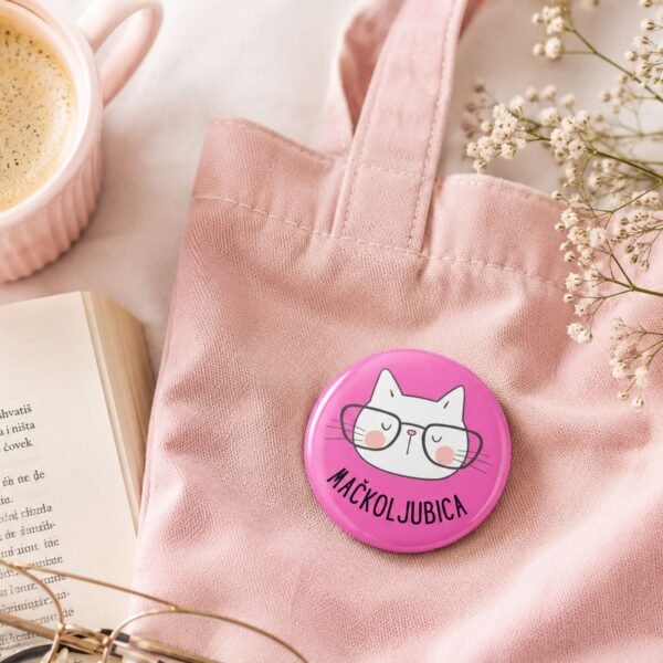 Roze Mačkoljubica bedž sa ilustracijom mačke na roze cegeru uz kafu i knjigu – cozy dodatak za ljubitelje mačaka